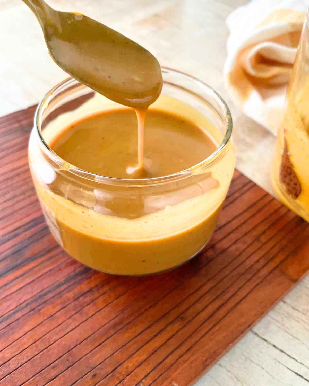 Side view image of Carolina Gold BBQ Sauce being dripped from spoon in a bowl