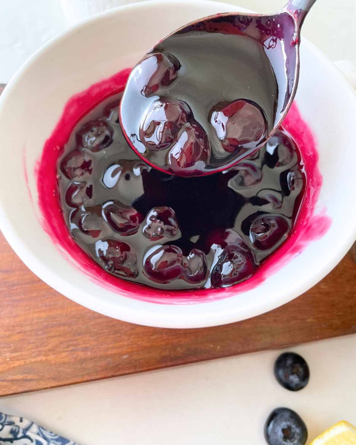 Spoon holding Classic Blueberry Sauce from the bowl