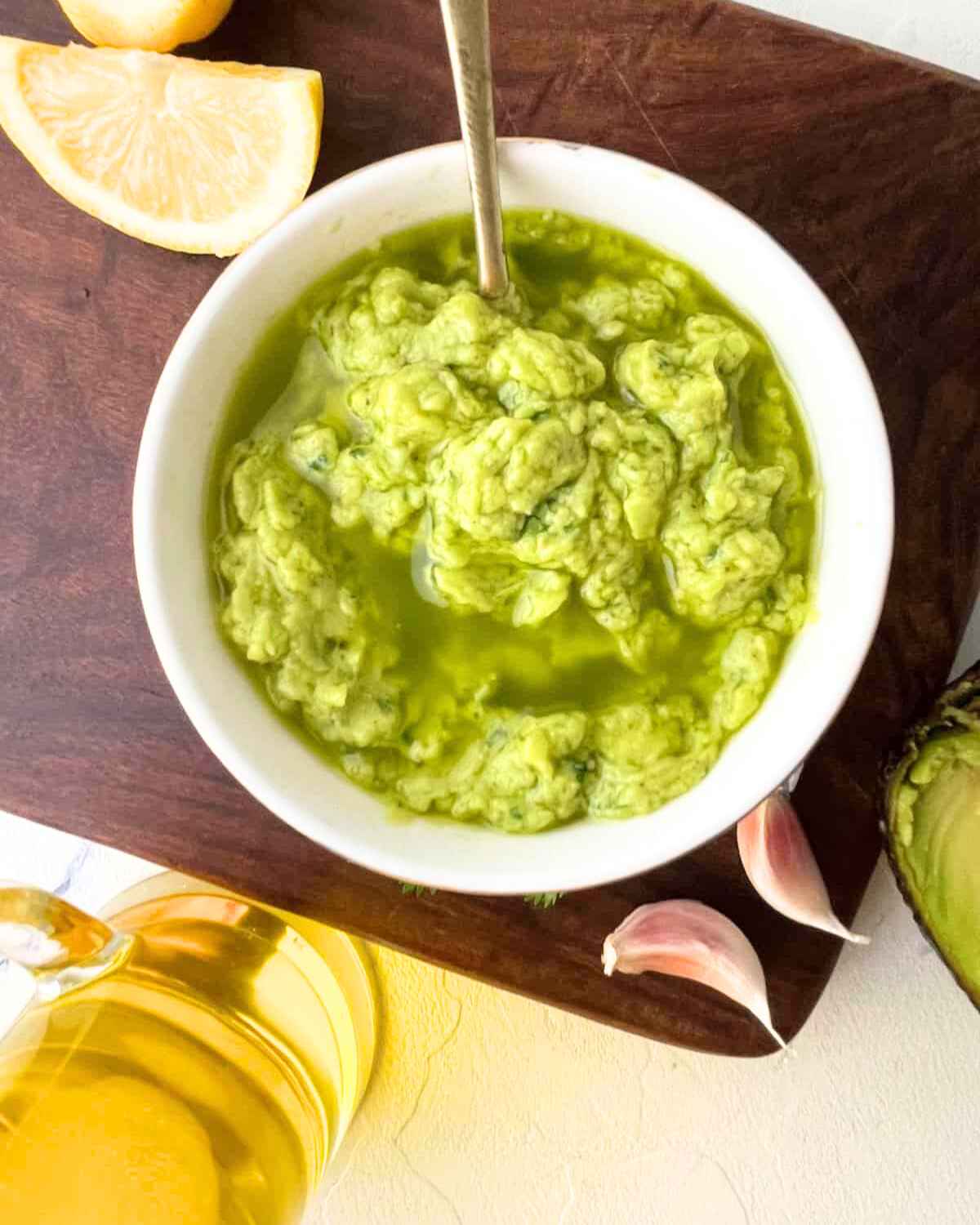 Garlic Avocado Spread in a bowl with lemon wedges in the background