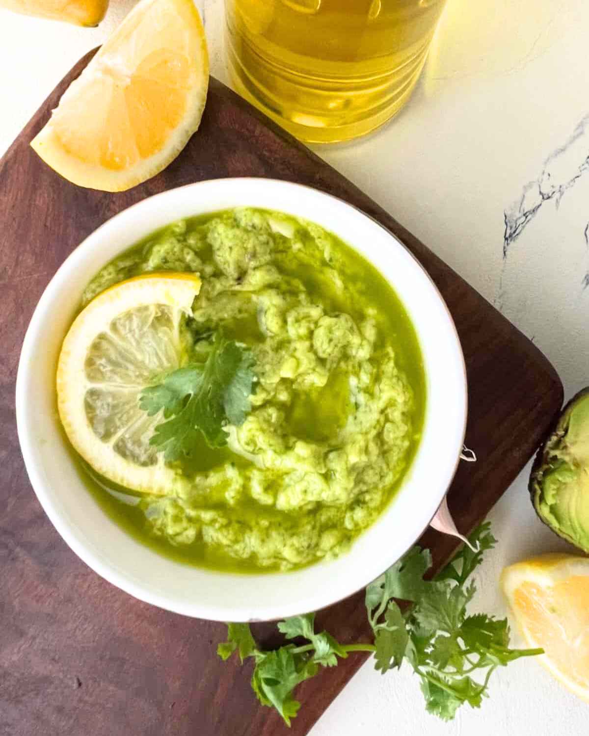 Top view of Garlic Avocado Spread in a bowl with a lemon slice 