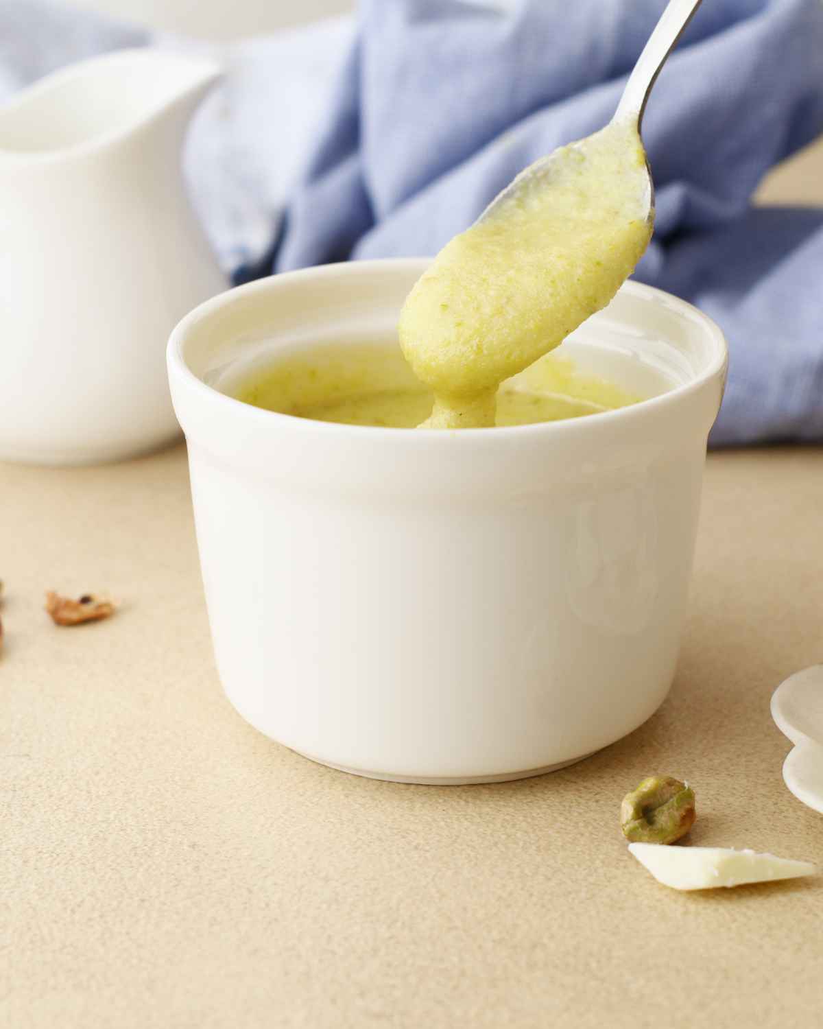 A spoon holding Pistachio Pastry Cream from bowl