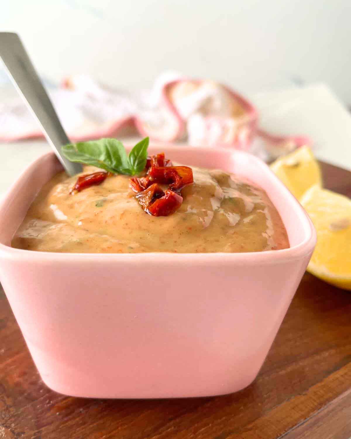 Side zoom in image view of Sun Dried Tomato Aioli with spoon in pink bowl