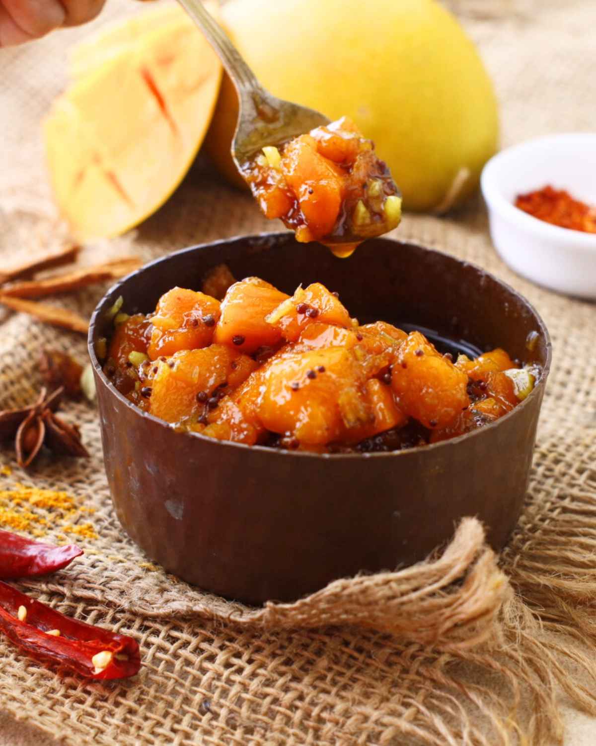 A spoon carrying Ginger Mango Chutney from the bowl 