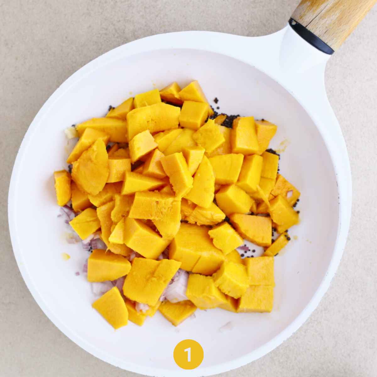 Diced Mango being sauted with chopped onions and mustard seeds in a pan  