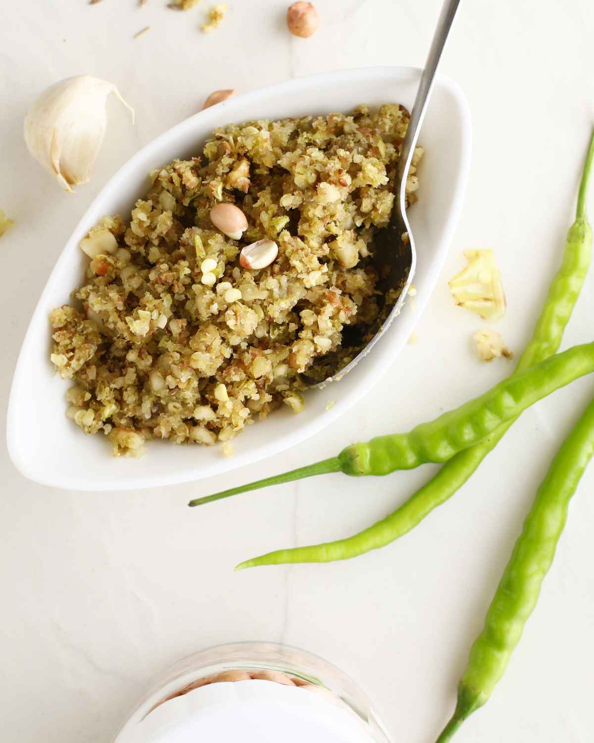 Green Chili Thecha in bowl with fresh green chilies in the background